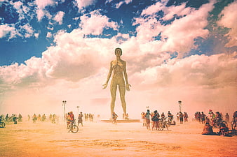 Giant wireframe statue at desert art festival with crowd and bikes