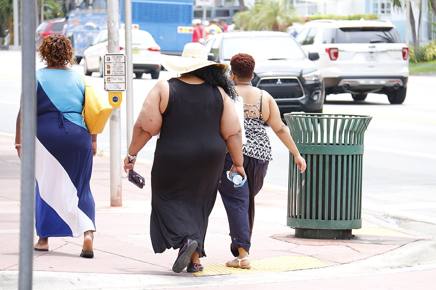 Three women walking away on a sunny city sidewalk