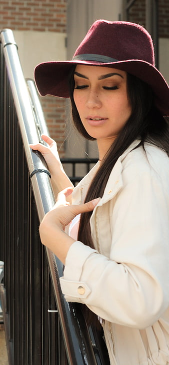 Woman in Burgundy Hat and White Jacket Leaning on Railing