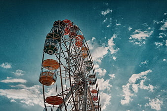 Vintage Ferris Wheel Against Blue Sky with Clouds