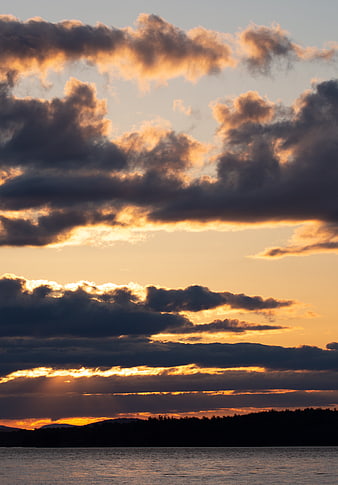 Dramatic sunset over lake with golden clouds and silhouette