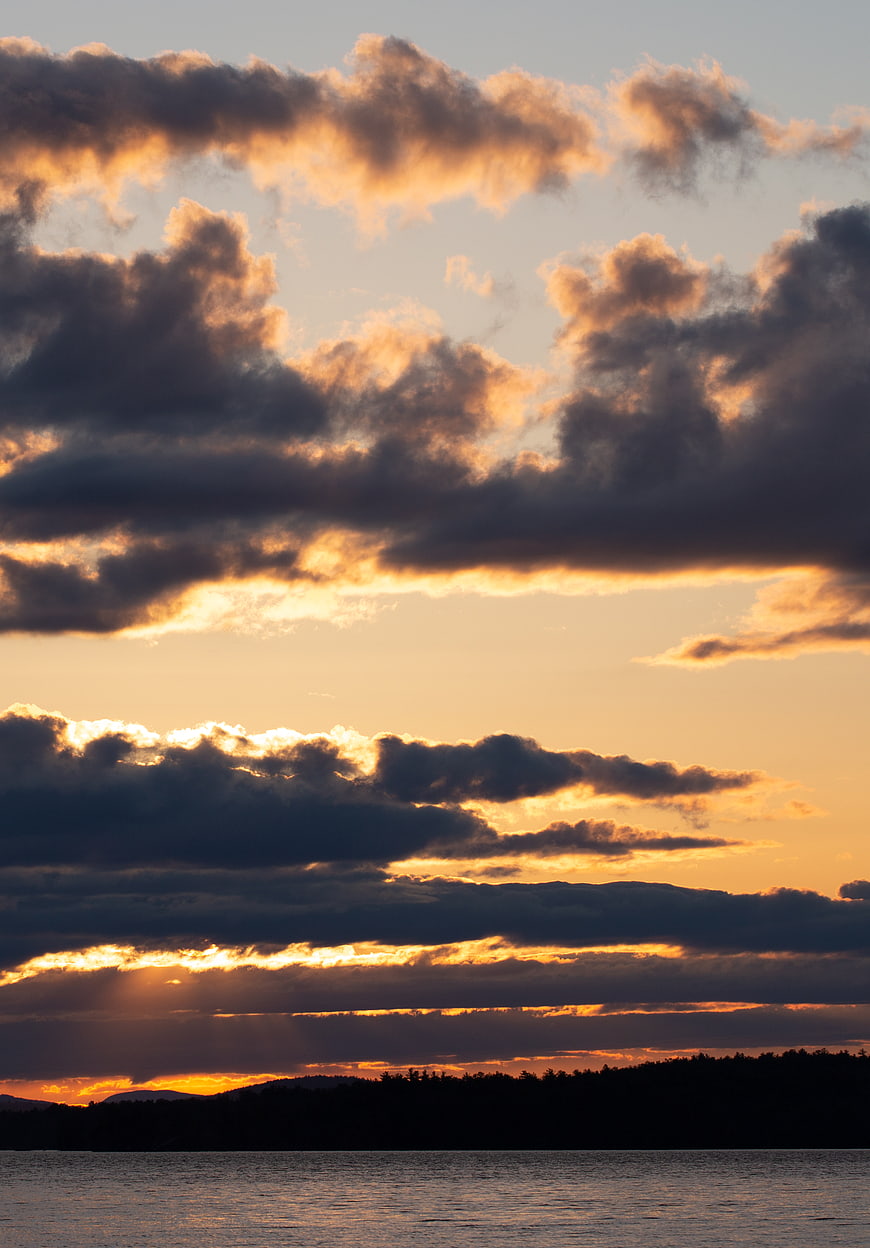 Dramatic sunset over lake with golden clouds and silhouette