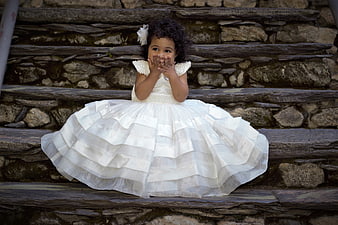 Cute little girl in white dress sitting on stone steps