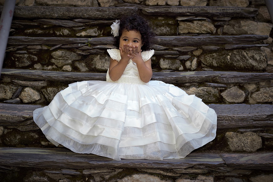 Cute little girl in white dress sitting on stone steps