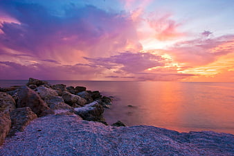 Dramatic purple and orange sunset over rocky ocean coastline