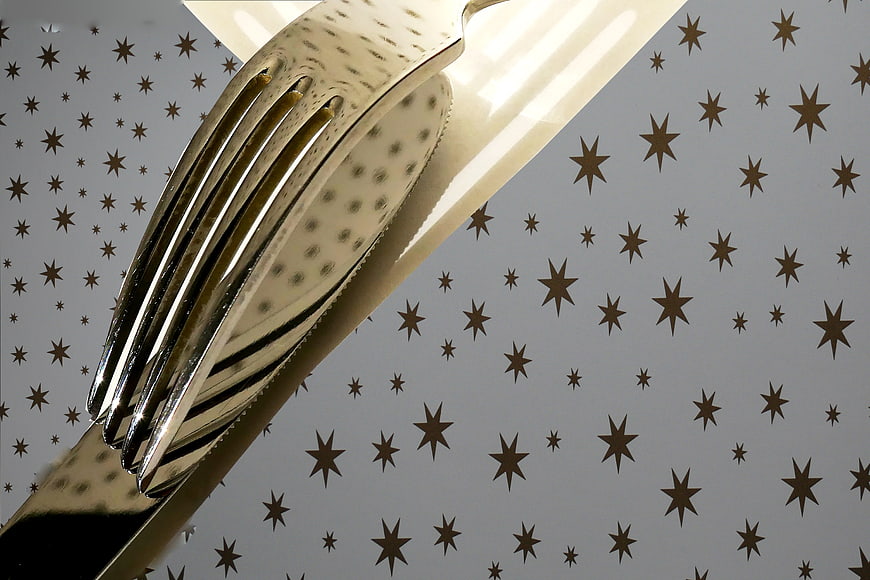 Close-up of shiny silver fork on star-patterned background