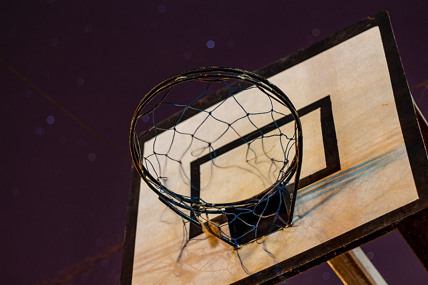 Close-up of weathered basketball hoop and net at night