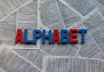 Colorful foam letters spelling alphabet on newspaper background