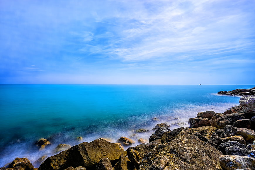 Serene Blue Ocean Coastline with Rocky Shore and Misty Waves