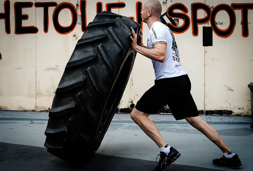 Athletic Man Flipping Large Tractor Tire for CrossFit Workout