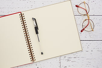 Flat lay of blank notebook, pen, and glasses on white desk