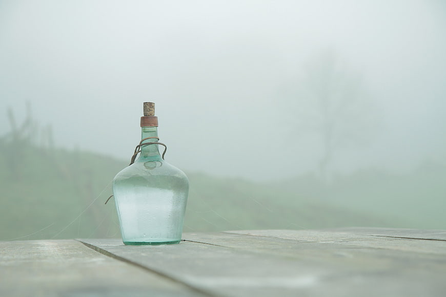 Vintage glass bottle with message in a bottle on foggy wooden table