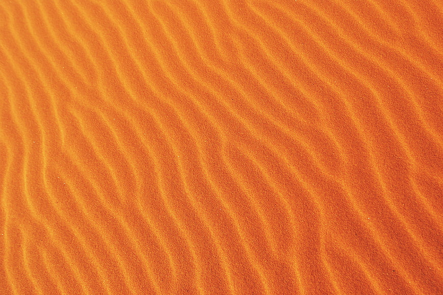 Close-up of rippled orange sand texture pattern