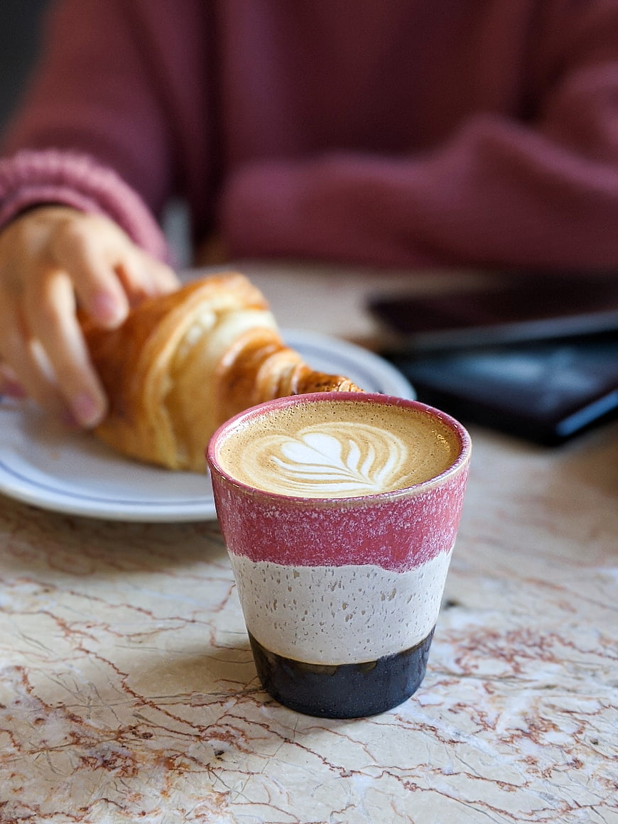 Cappuccino with latte art and croissant on marble table