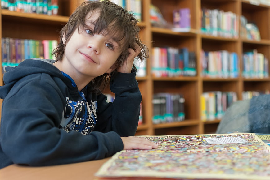 Thoughtful young boy in library with book
