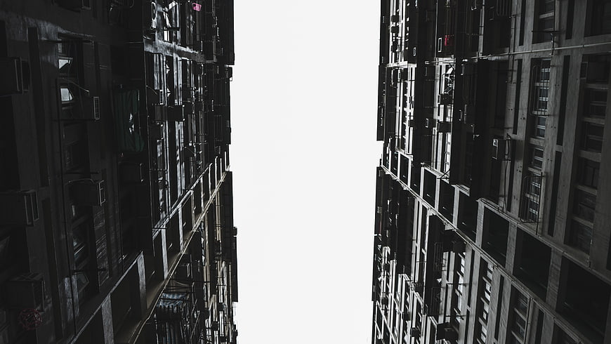 Low angle view of tall apartment buildings with white sky