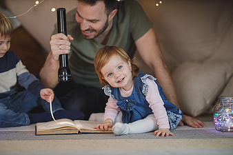 Happy Family Reading Bedtime Story with Flashlight Indoors