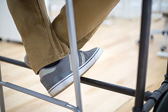 Close-up of man's feet in grey sneakers on office chair