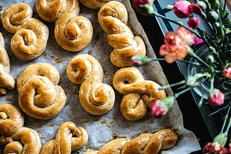 Freshly baked sweet wheat buns on baking sheet with flowers