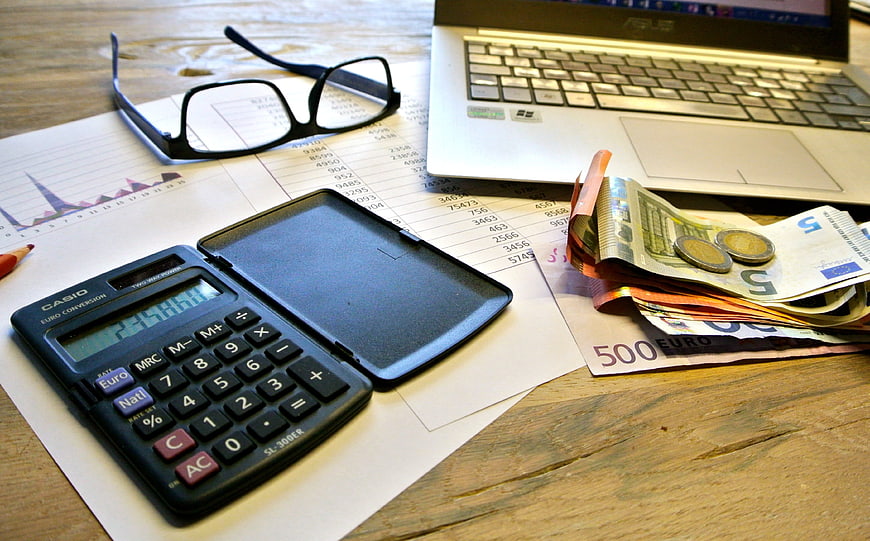 Business Finance Workspace With Calculator, Laptop, And Currency
