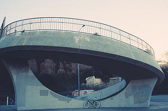 Modern curved concrete bridge with bicycle underneath