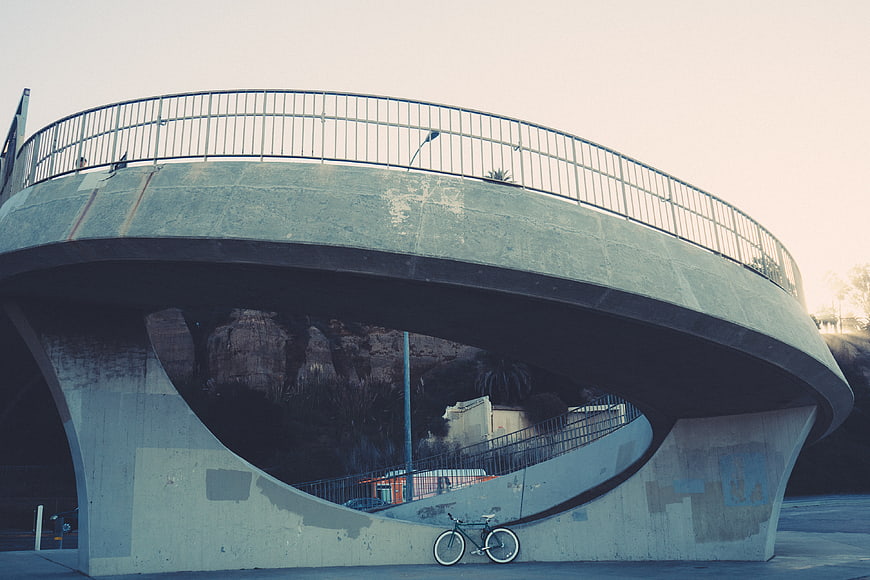 Modern curved concrete bridge with bicycle underneath