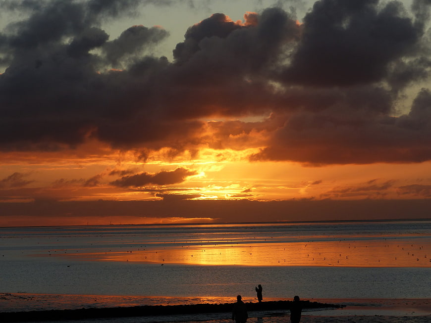 Dramatic Sunset Over Wadden Sea with Silhouetted Figures