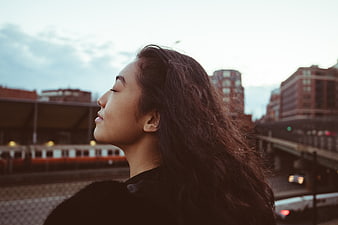 Serene Woman with Eyes Closed on Urban Train Platform