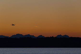 Silhouette of Airplane Landing Over Lake at Sunset