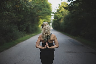 Blonde woman meditating on a quiet forest road