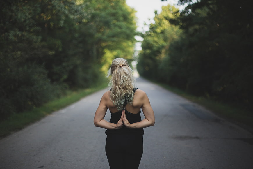 Blonde woman meditating on a quiet forest road