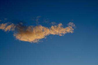 Golden sunset cloud against deep blue sky background