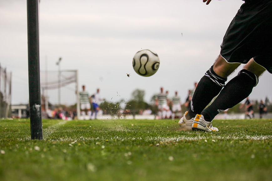 Low angle soccer player kicking ball on grass field