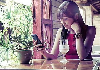 Woman in red dress looking at smartphone in cafe