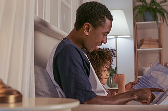 Father reading bedtime story to young daughter on bed