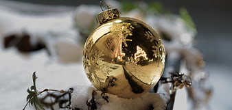 Golden Christmas Ornament in Snow with Reflections