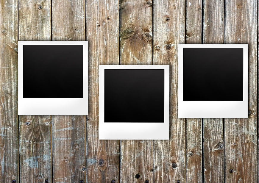 Three blank polaroid frames on rustic wooden background