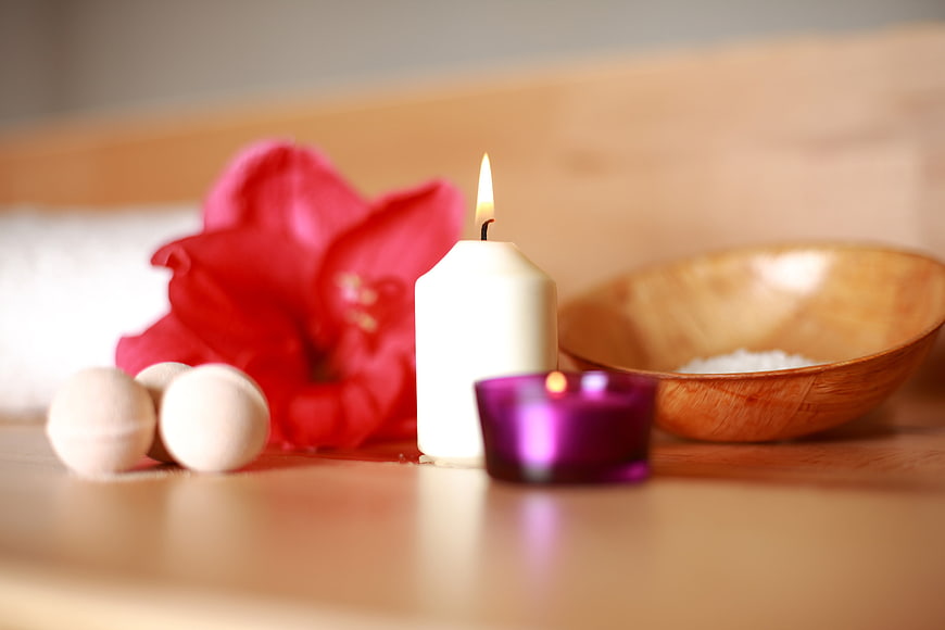 Spa relaxation setup with candles, flower, and bath salts