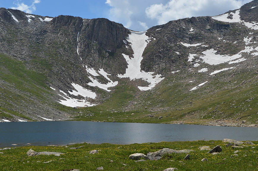 Alpine lake with snow-capped mountains and wildflowers