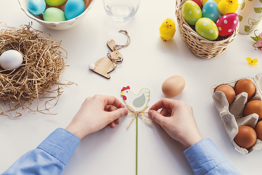 Hands crafting Easter chicken decoration with eggs and nest