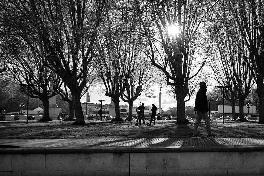 Black and white photo of people walking in Paris park with trees