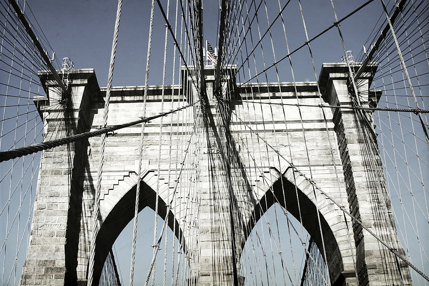 Low angle view of Brooklyn Bridge stone tower and cables