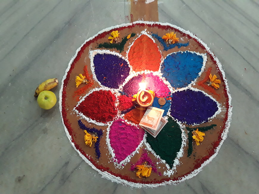 Colorful Rangoli Art with Diya and Offerings on Floor