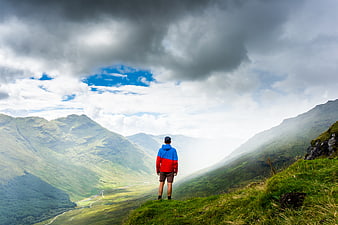 Hiker standing on mountain ridge overlooking green valley