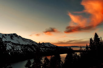 Dramatic sunset over snow-capped mountains and lake