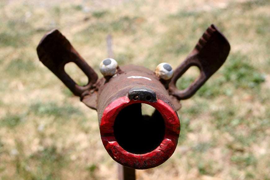 Rusty Metal Pipe Sculpture With Cartoon Eyes And Red Rim