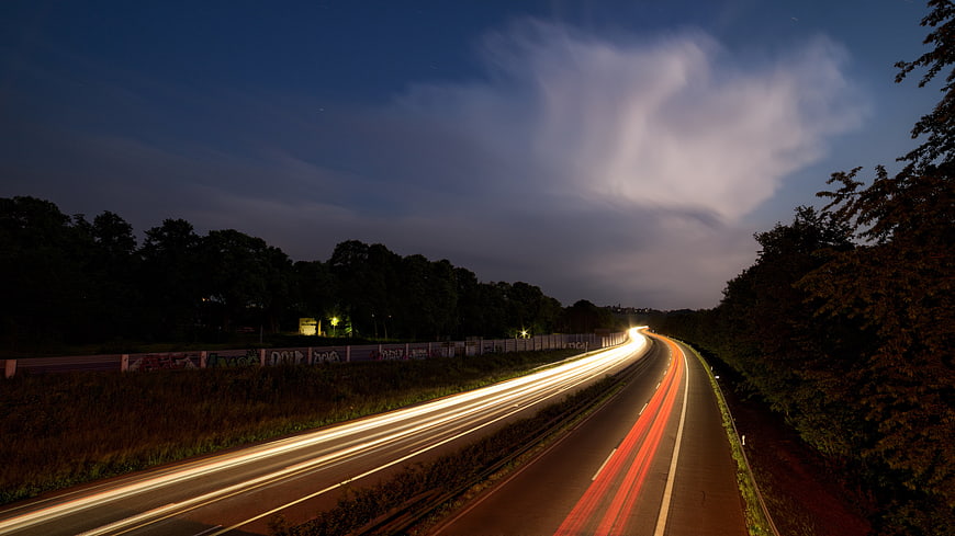 Highway Light Trails at Night with Dramatic Clouds