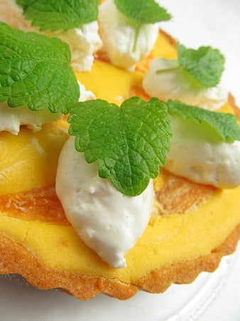 Close-up of mango tart with cream and mint garnish