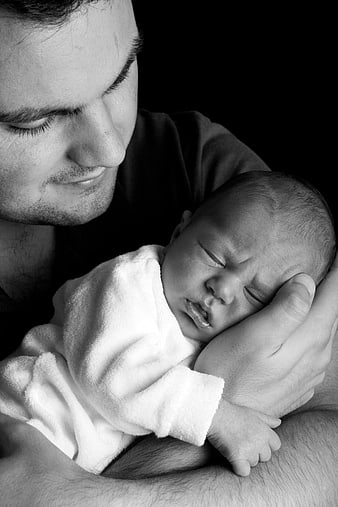 Black and white portrait of father holding sleeping newborn baby