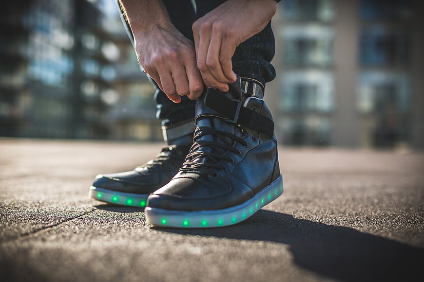 Man tying black sneakers with glowing green LED soles